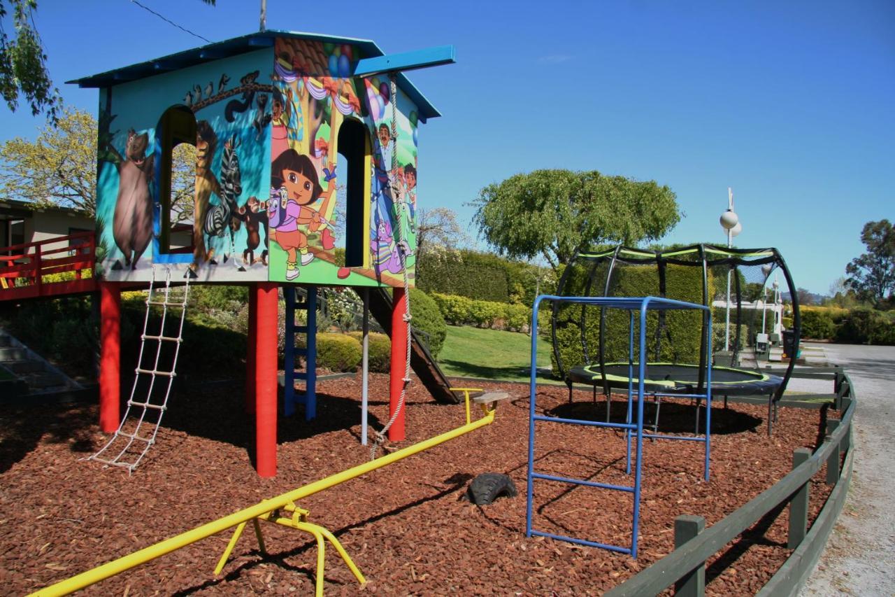 Taupo Debretts Spa Resort Екстер'єр фото The photo shows a colorful playground structure that resembles a small house. It features a mural with animated characters on one side, likely including familiar children's figures. The house has ladders for climbing and a slide. Nearby, there is a c